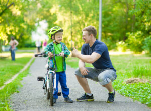 Father teaching a boy to ride a bike and giving him the thumbs up