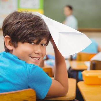 student about to throw a paper plane in a classroom