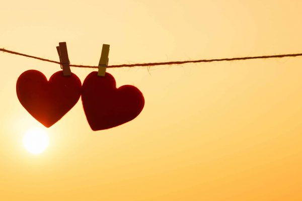 Two hearts pegged onto a line in the sunset