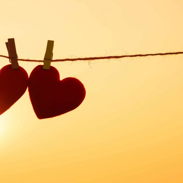 Two hearts pegged onto a line in the sunset