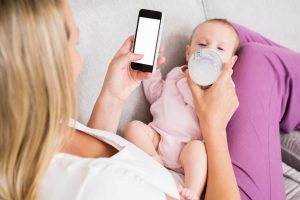 Mother feeding her baby while using a phone
