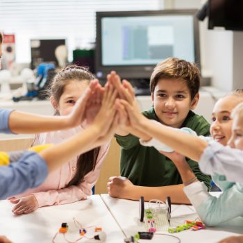 Kids in a science classroom doing a group high five