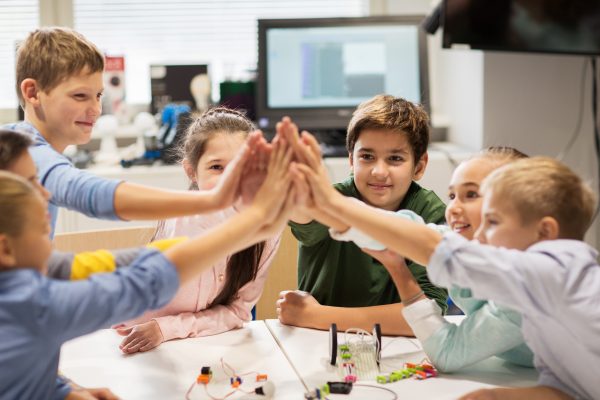 Kids in a science classroom doing a group high five