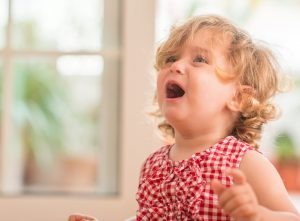 Blond child wearing red crying at home