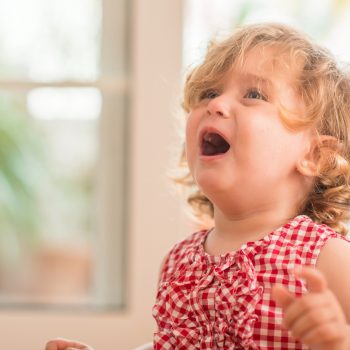 Blond child wearing red crying at home